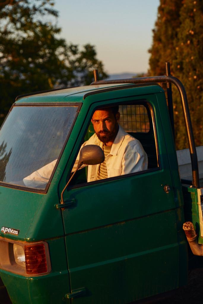 founder of Agricola Maraviglia sitting inside a green truck with trees in the background